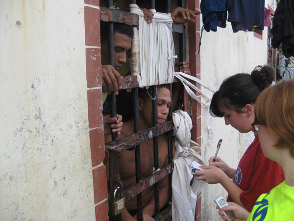 Two students take notes as two prisoners look through bars from a jail cell