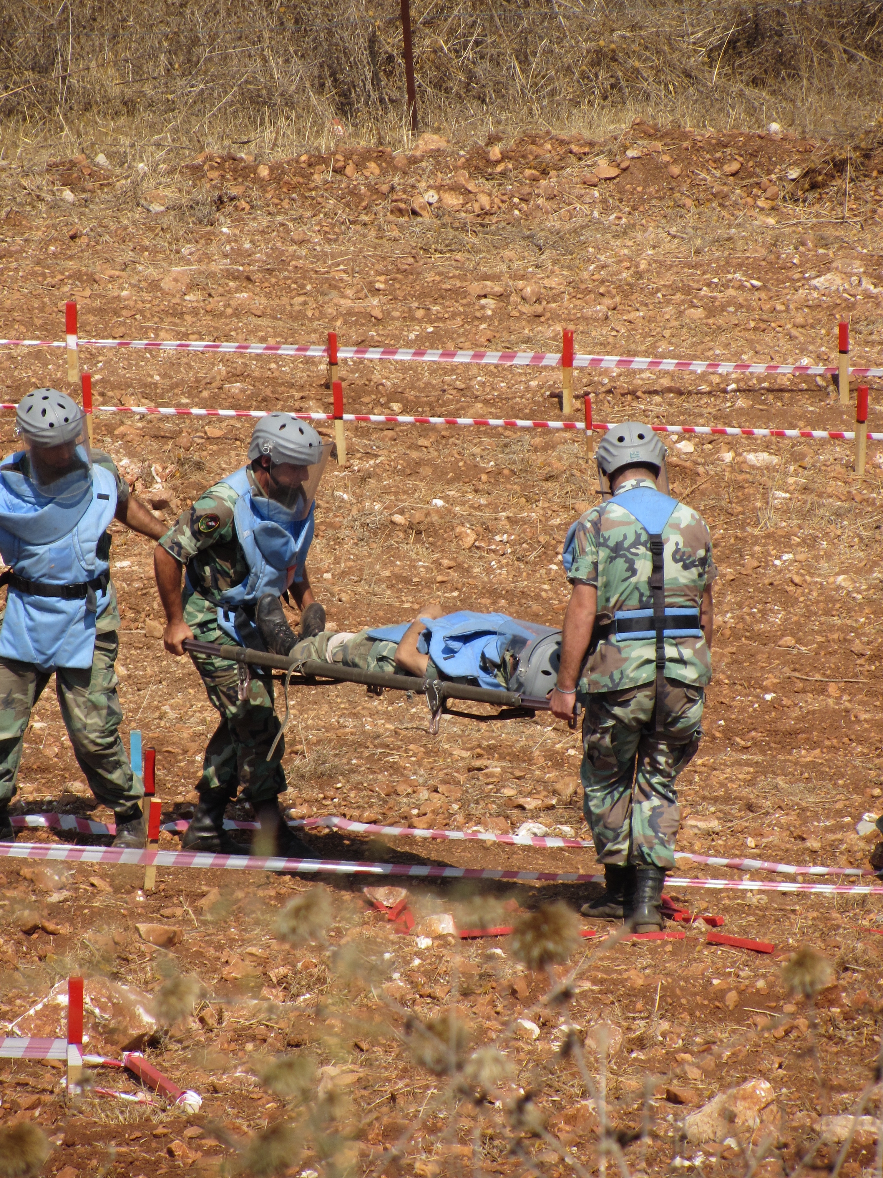 Military members wearing camouflage garb carry a stretcher with a body.