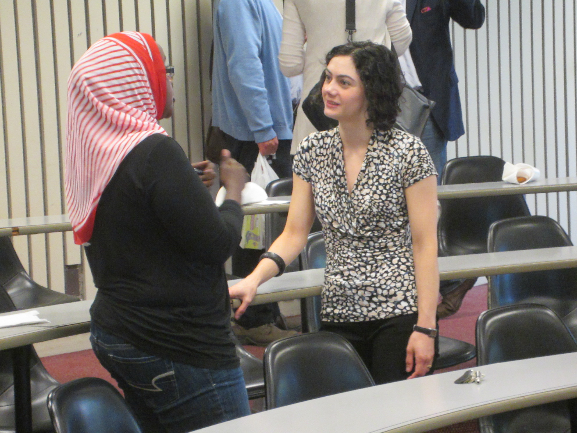 Susan Farbstein stands talking to a student wearing a hijab in a classroom.