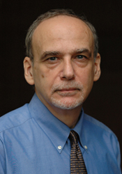 Headshot of a man with gray hair wearing a blue button down and tie.