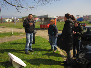 Ervin shows Bonnie (center) and her clinical team a small monument at the site of the Keraterm concentration camp, now a tile factory, in Bosnia in 2013. Photo by Nicolette Boehland.