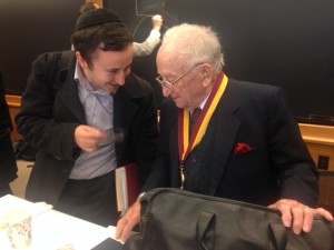 A student wearing a yammakah bends down over Ben Ferencz.