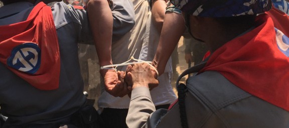 Police battalion officers detain a protester whose hands have been bound with plastic ties, March 10, 2015. Police arrested 127 protesters, journalists, and bystanders in Letpadan on March 10. At least 50 protesters remain behind bars at the time of writing. ©2015 Paul Mooney.