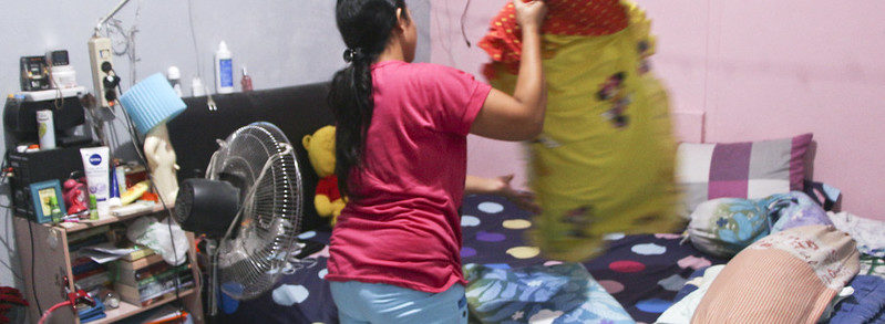 Domestic worker makes a bed and does laundry in Indonesia
