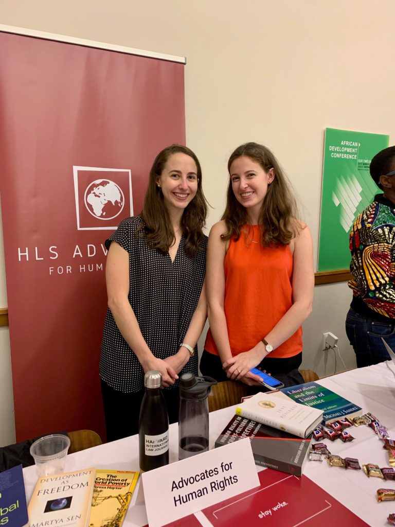 Two students standing at a table advertising HLS Advocates for Human Rights