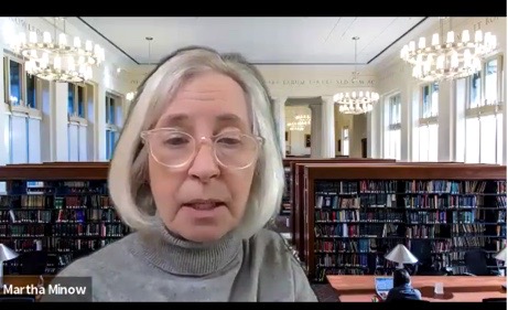 Martha Minow with white hair, glasses, and a grey turtleneck speaks on zoom.