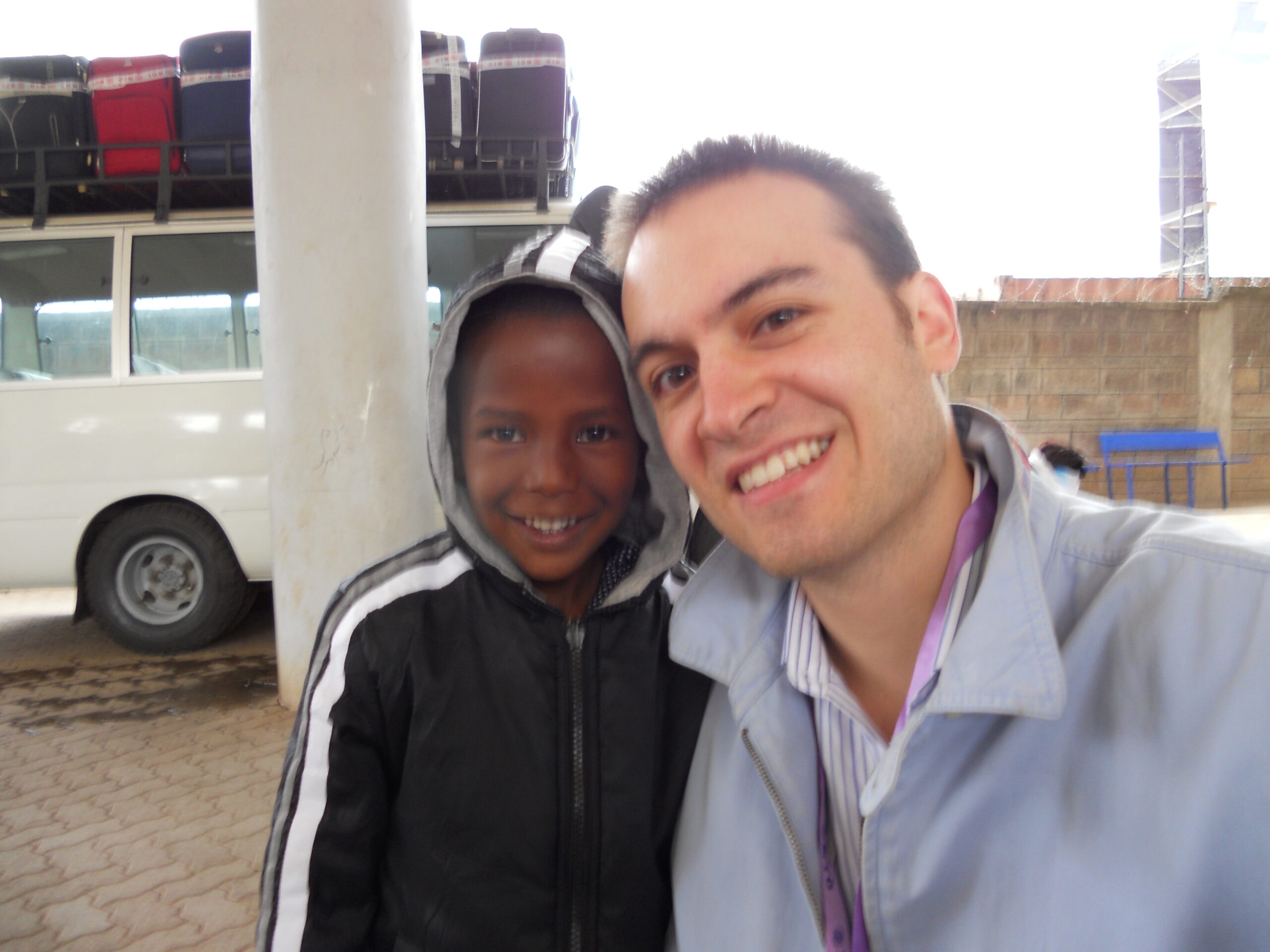 Brett Stark poses with a Kenyan child in front of a white column