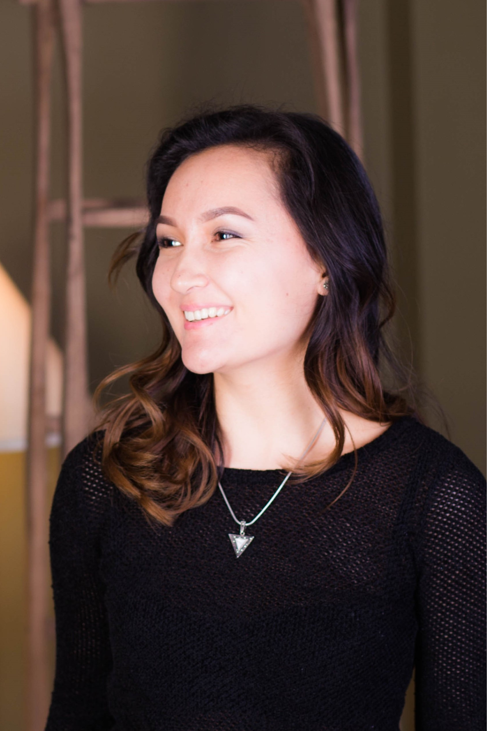 Photo of Aizhan Tilenbaeva. Aizhan is smiling and looking to the side. She is wearing a black sweater. 