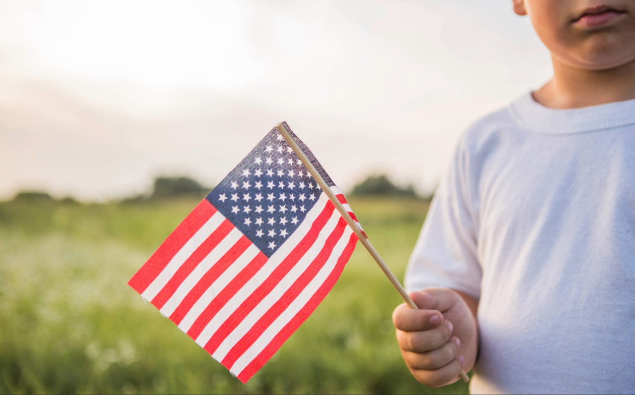 A child in a white t-shirt holding a U.S. flag