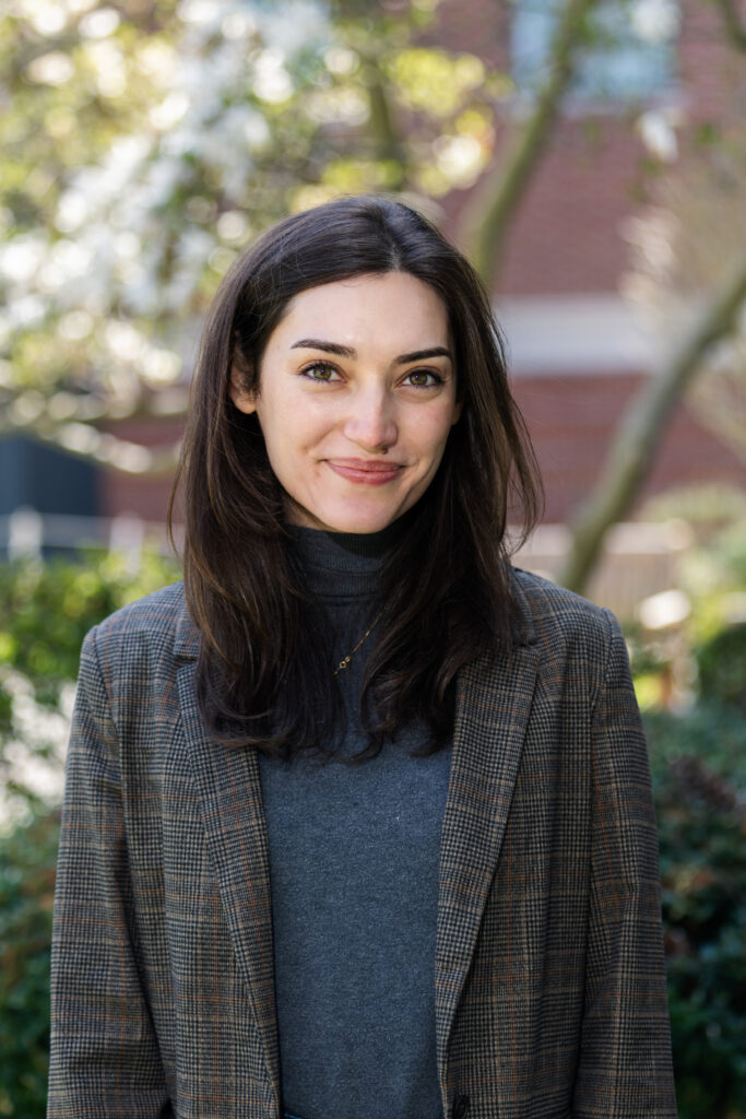 Headshot of a woman wearing a blazer, standing by a tree.